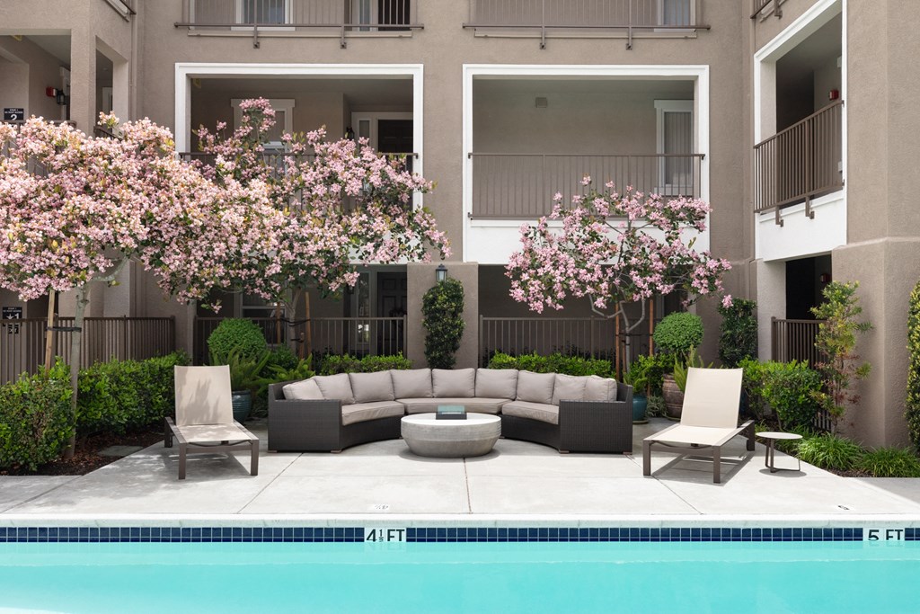 a patio with a couch and two chairs next to a pool