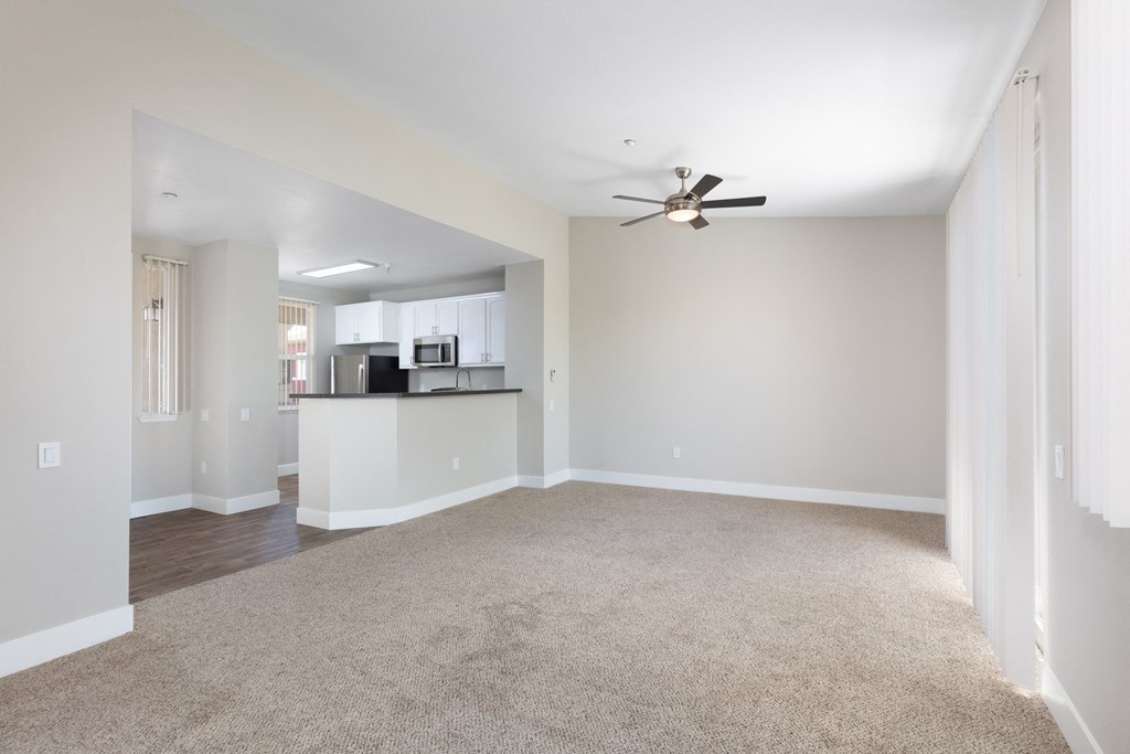 an empty living room with a ceiling fan