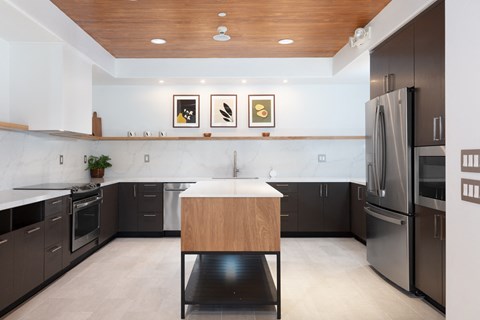 a kitchen with black cabinets and stainless steel appliances and a wooden table