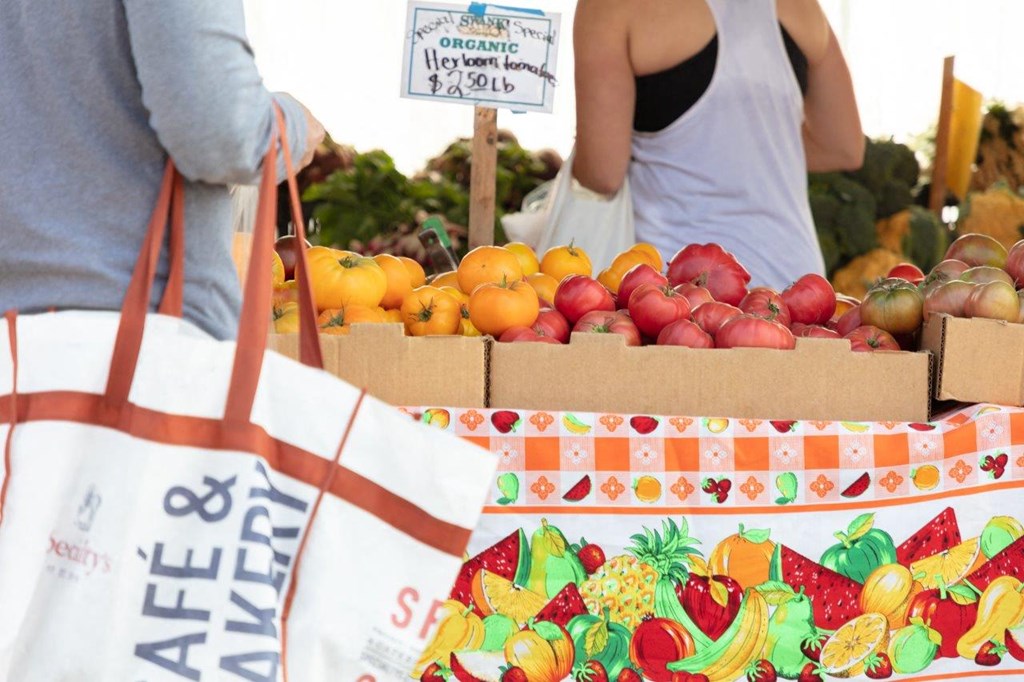 people buying fruit at a fruit stand at a farmers market
