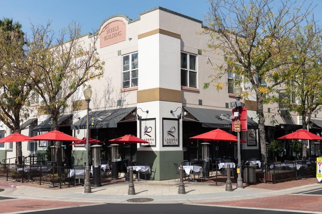 a building on the corner of a street with tables and umbrellas