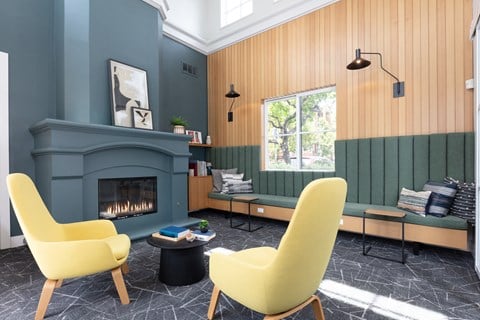 a living room with yellow chairs and a fireplace