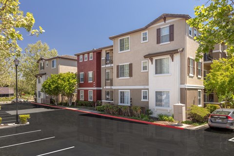 A parking lot in front of a multi-story apartment building.