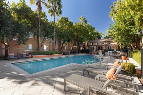 A pool surrounded by palm trees and lounge chairs.