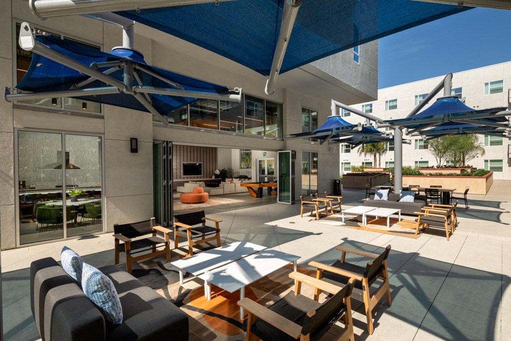 outdoor lounge with umbrellas and chairs at Aston at Gateway apartments in El Monte, California