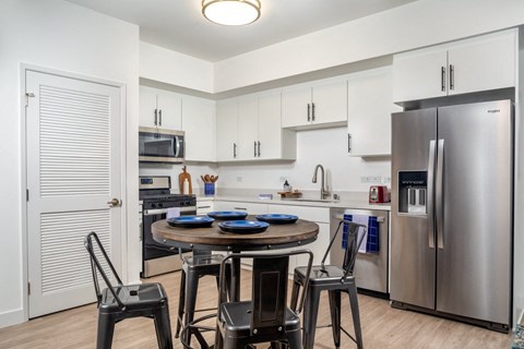 a kitchen with stainless steel appliances and a table with chairs