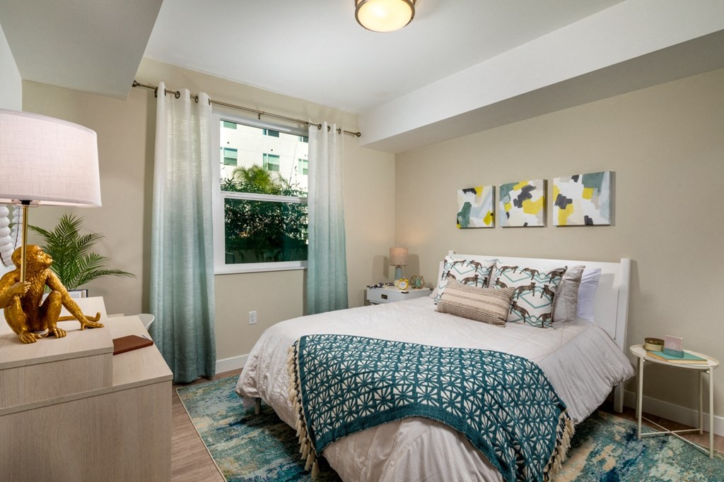 spacious bedroom with green accents and a window at Aston at Gateway apartments in El Monte, California