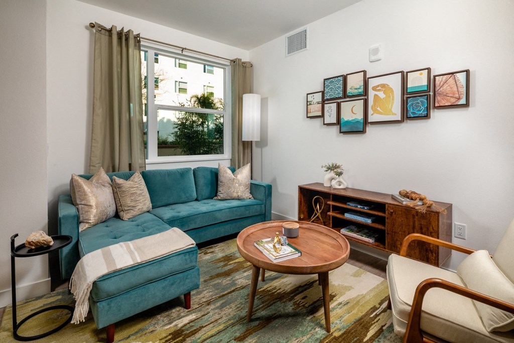 living room with large window and green furnishings at Aston at Gateway apartments in El Monte, California