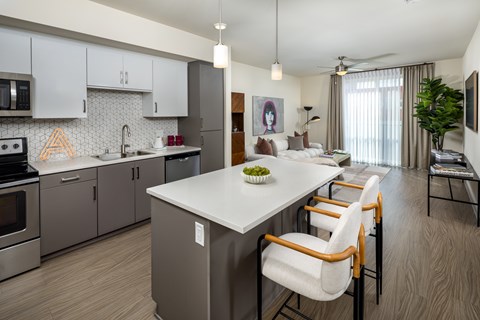 A modern kitchen with a white island and stainless steel appliances.