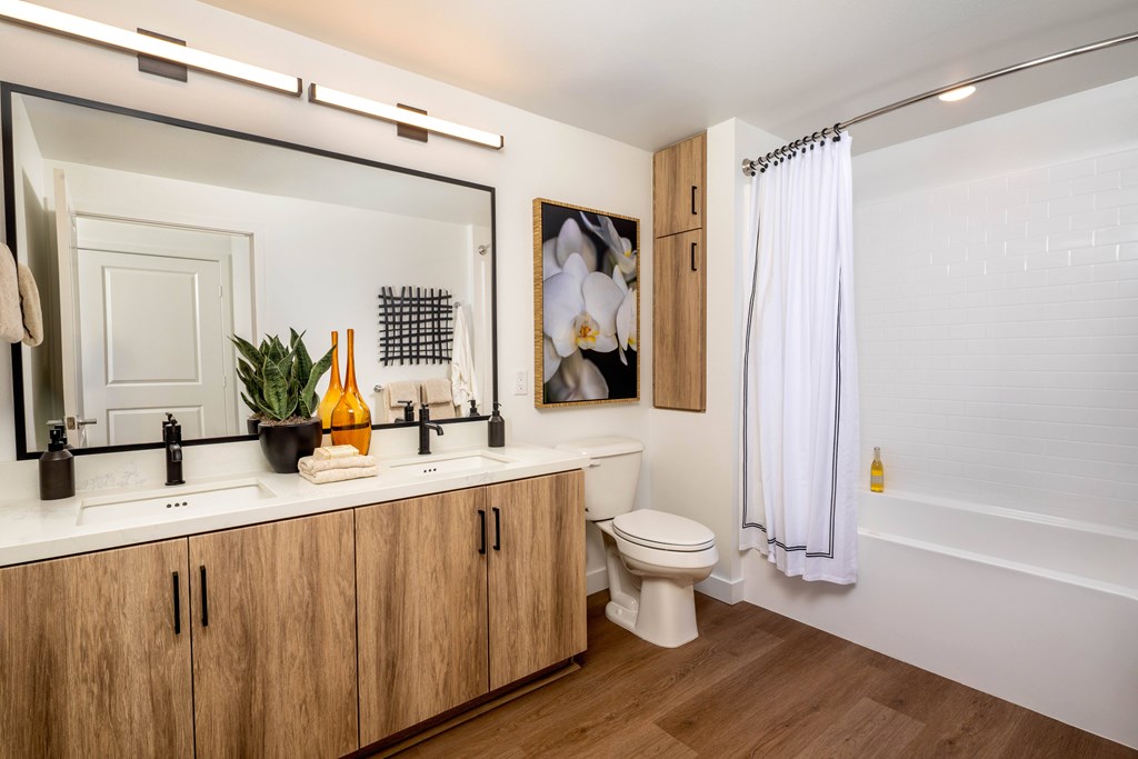 A white bathroom with wooden cabinets and a white toilet.