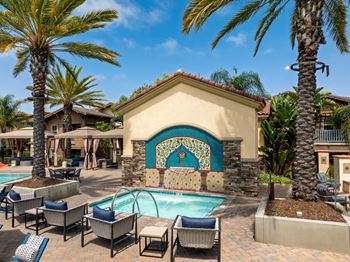 A pool area with a mosaic tile wall and lounge chairs.