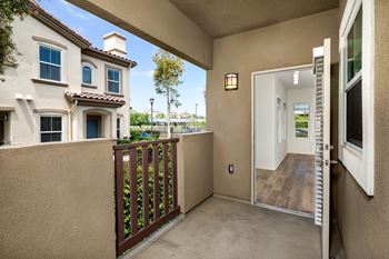 A balcony with a brown railing and a white door.