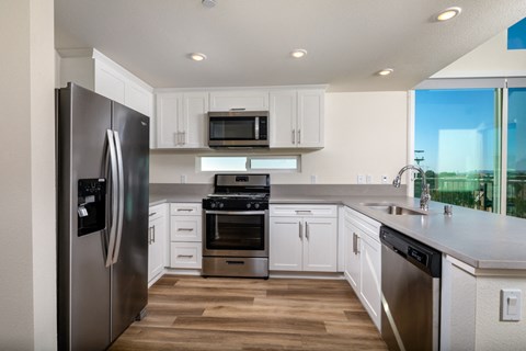 a large kitchen with stainless steel appliances and white cabinets