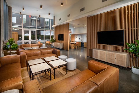 A modern living room with brown leather furniture and a flat screen TV mounted on a wooden wall.