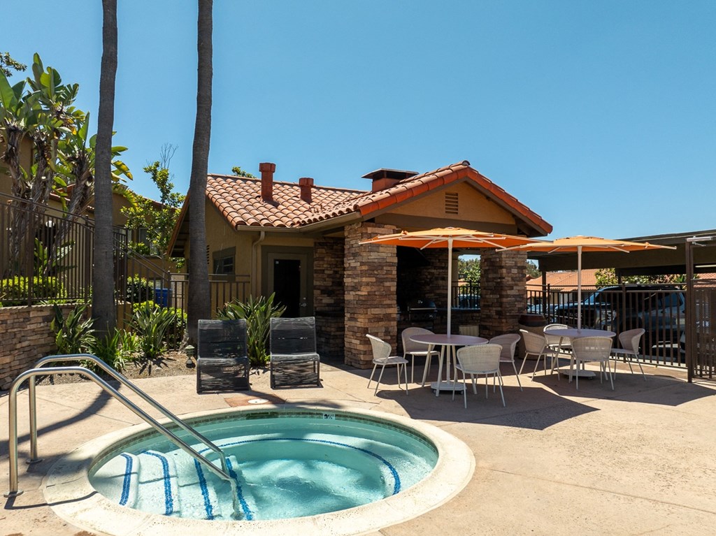 a jacuzzi and patio with tables and chairs in front of a house