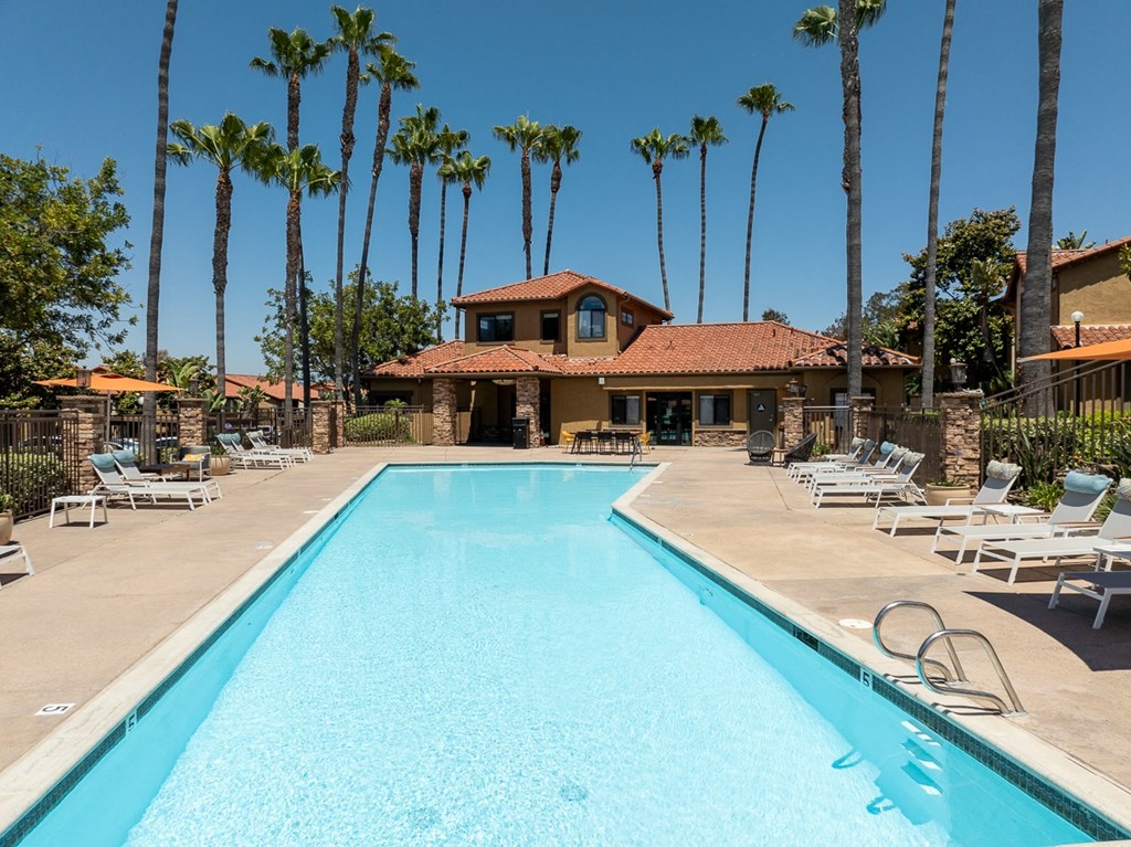 a swimming pool with chairs and a house in the background