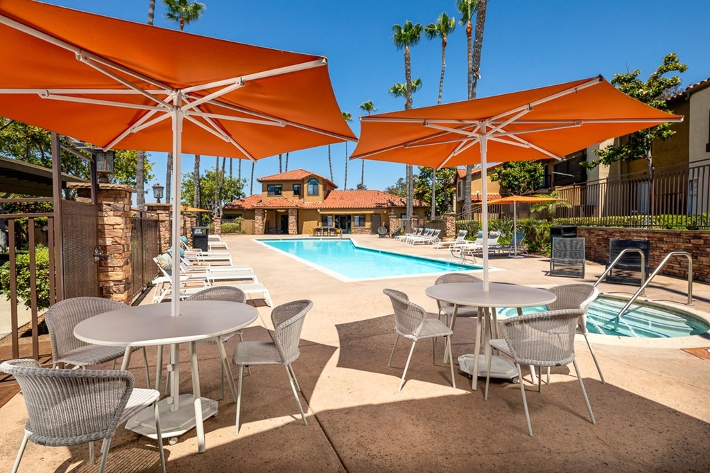 a swimming pool with tables and umbrellas next to it