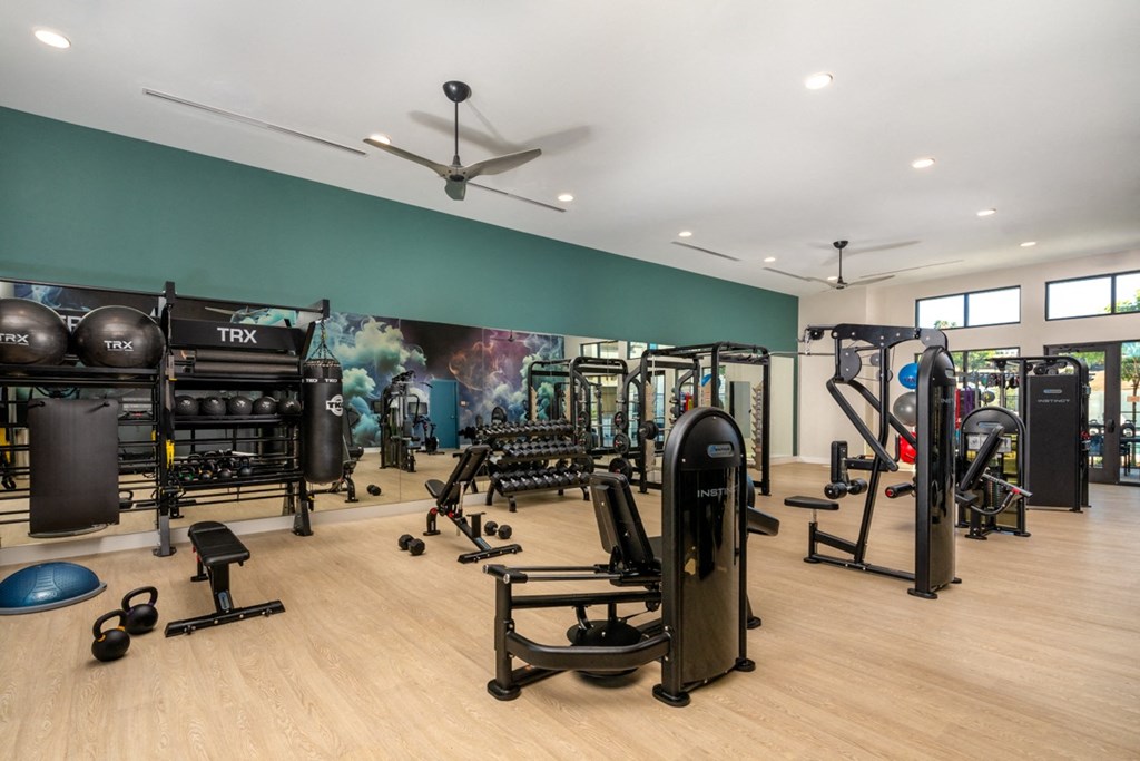 a fitness room with weights and cardio equipment and a large wall mural of a gym
