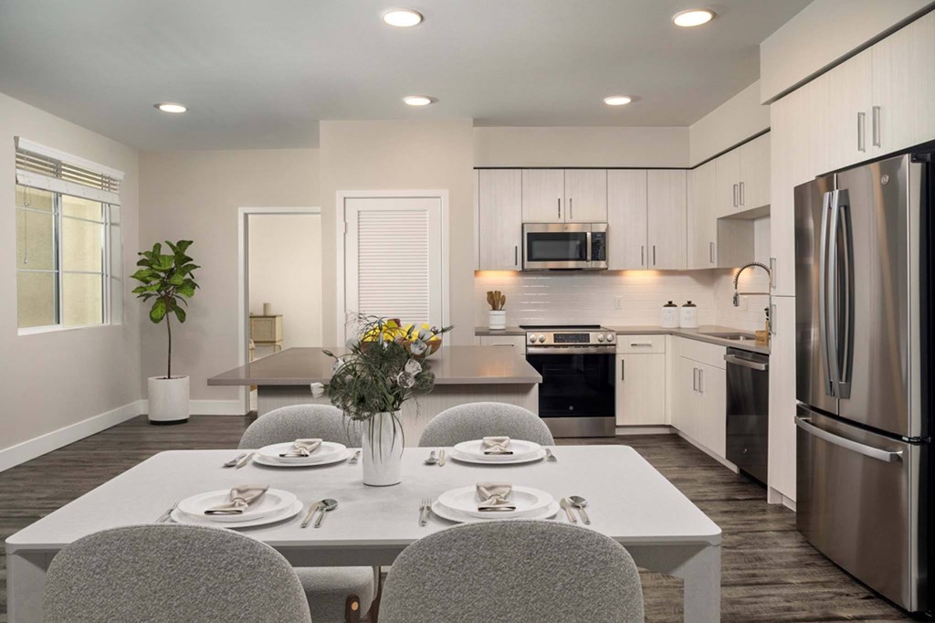 A modern kitchen with a dining table set for two.