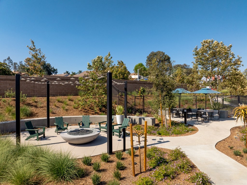 an outdoor seating area with chairs, a firepit and umbrellas
