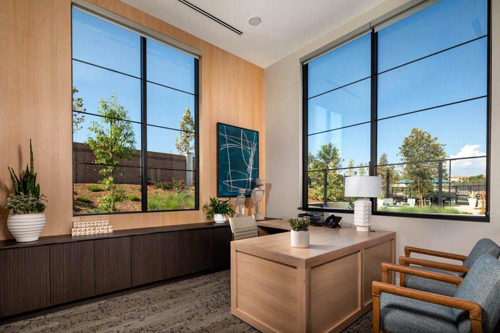 an office with large windows and a desk and chairs