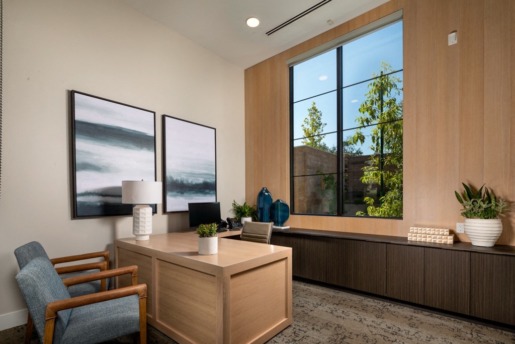 an office with a desk and three large windows