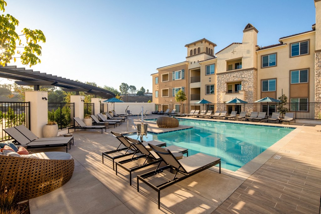 a swimming pool with lounge chairs and a building in the background