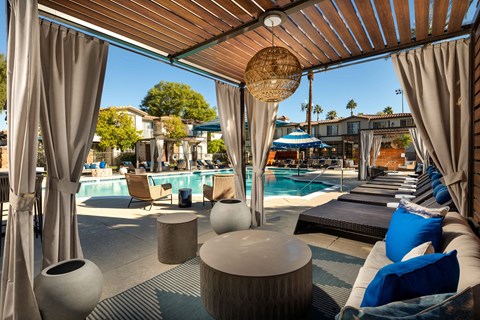 A poolside lounge area with blue cushions and a wooden ceiling.