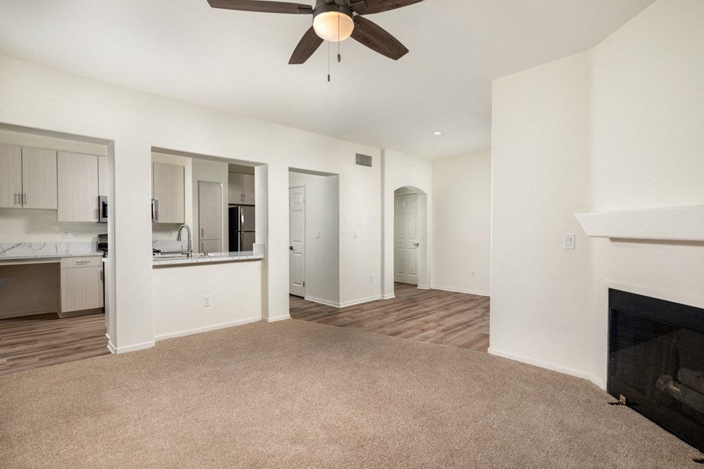 Empty living room with a fireplace and a ceiling fan at Casoleil, San Diego, CA