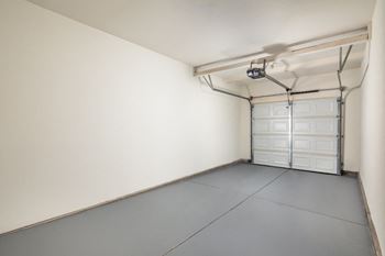 A garage with a white door and a grey floor.