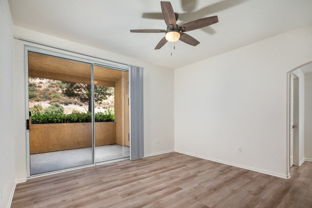 Empty living room with a ceiling fan and sliding glass doors at Casoleil, San Diego, CA