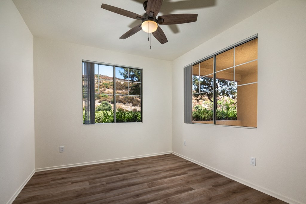 Empty living room with a ceiling fan and two windows at Casoleil, San Diego