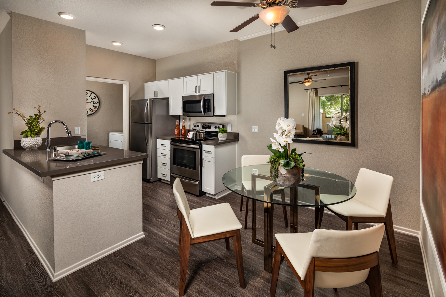 A modern kitchen with a glass table and white chairs.