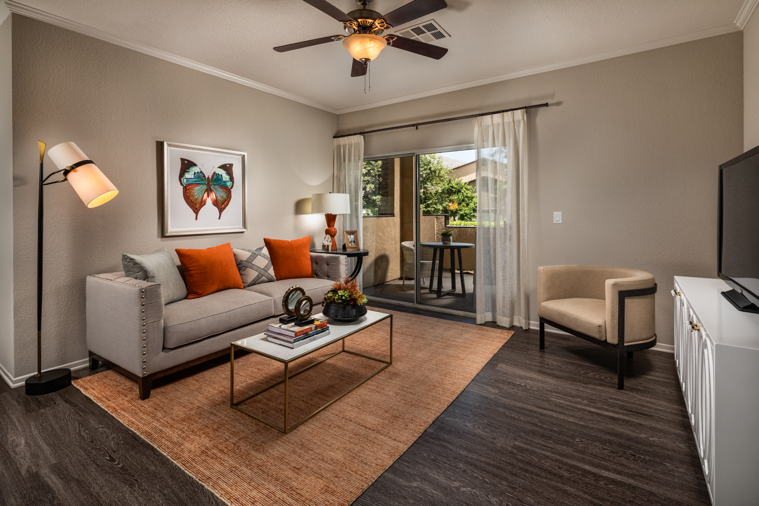 A living room with a grey couch, a coffee table, a television, and a painting on the wall.