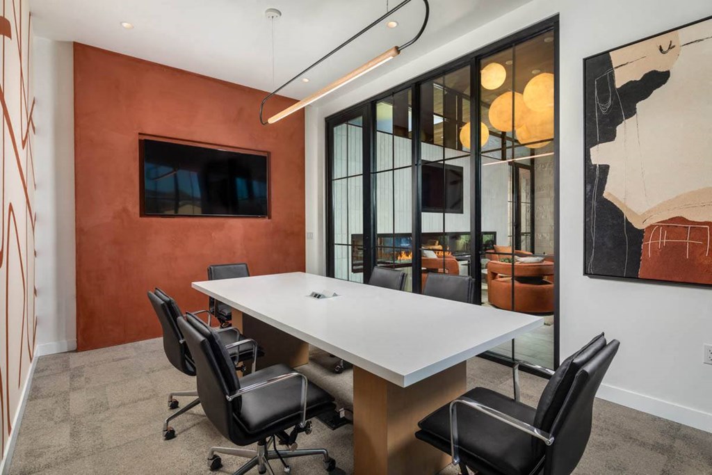 A conference room with a white table and black chairs.