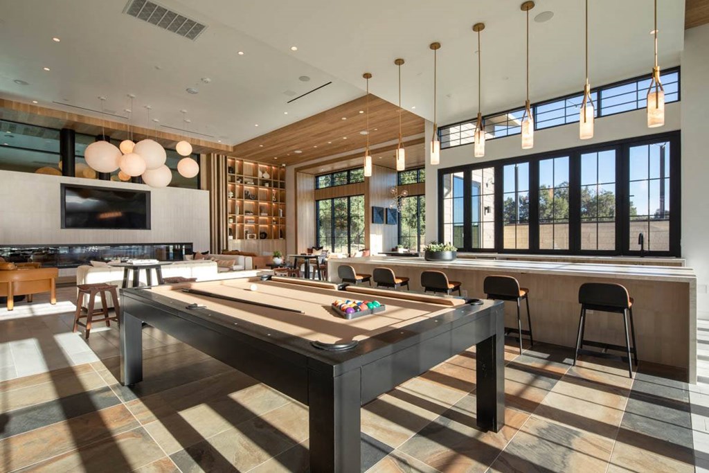 A room with a pool table and a bar area.