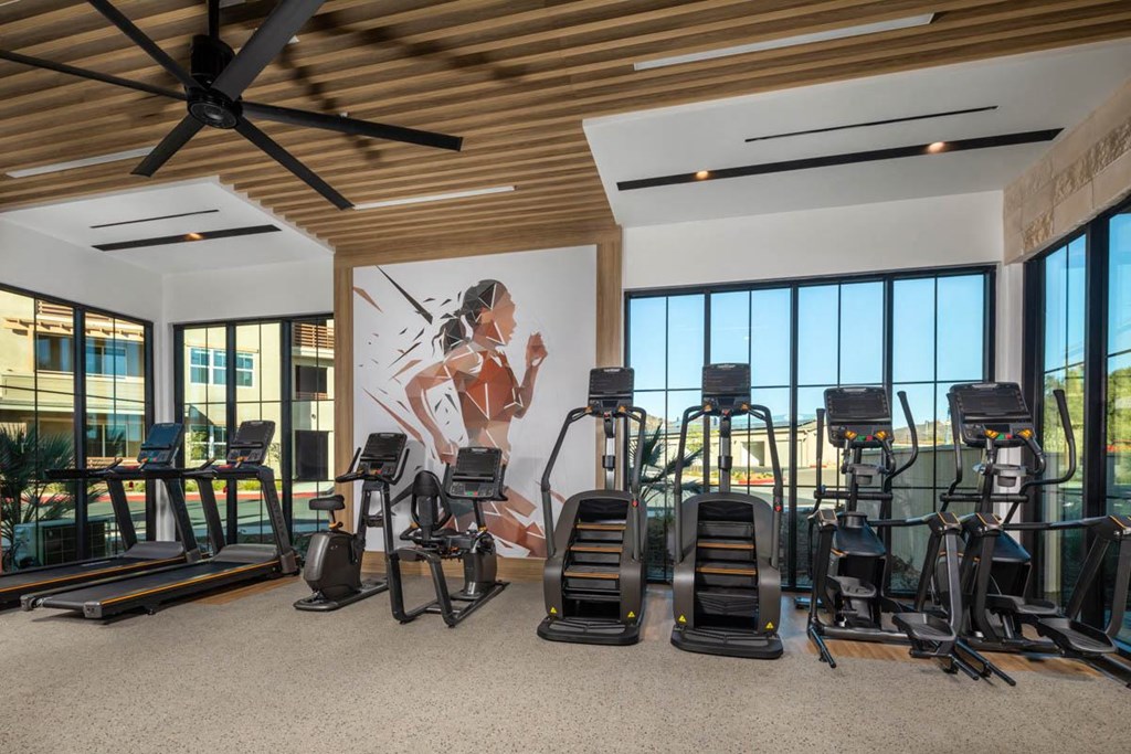 A gym with treadmills, exercise bikes, and a wall mural.