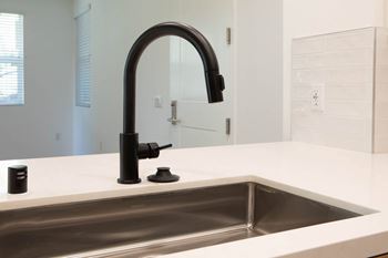 A modern kitchen sink with a black faucet.