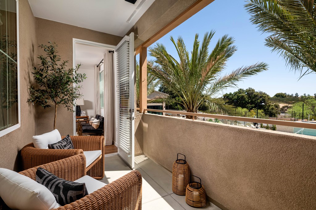 A patio with a couch, chairs, and a table with a plant on it.