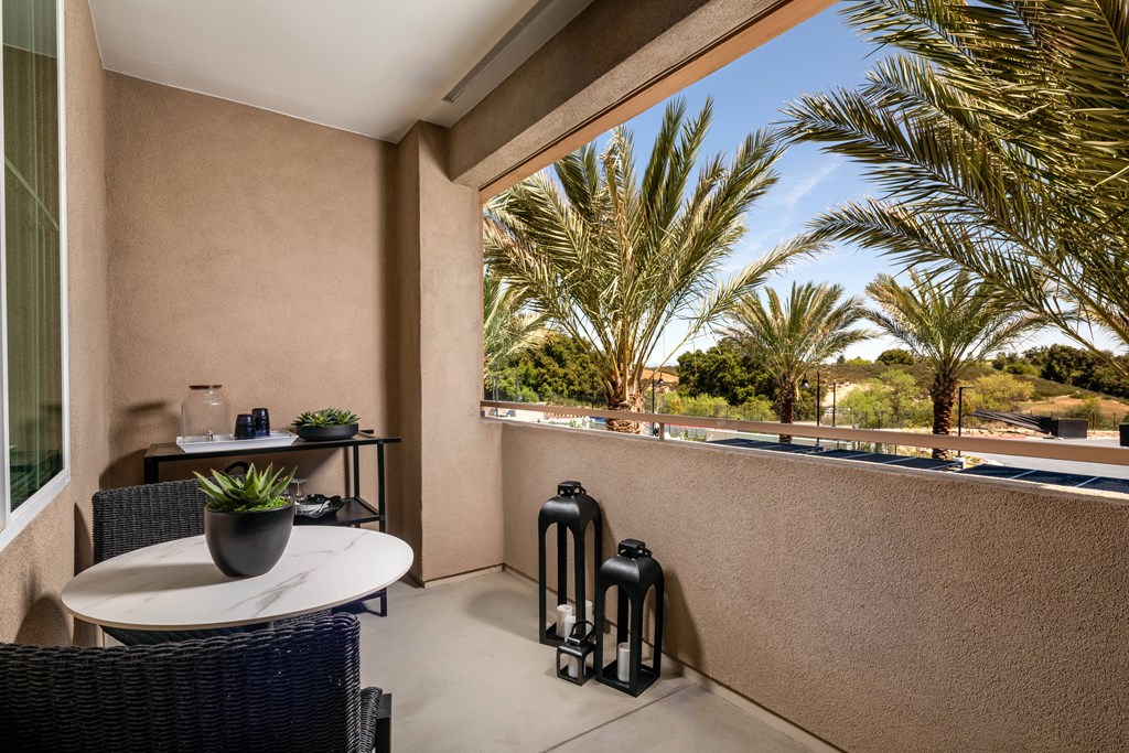 A patio with a table and chairs overlooking a palm tree.