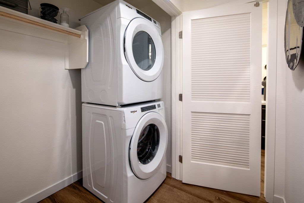A white washing machine and dryer stacked on top of each other in a small room.
