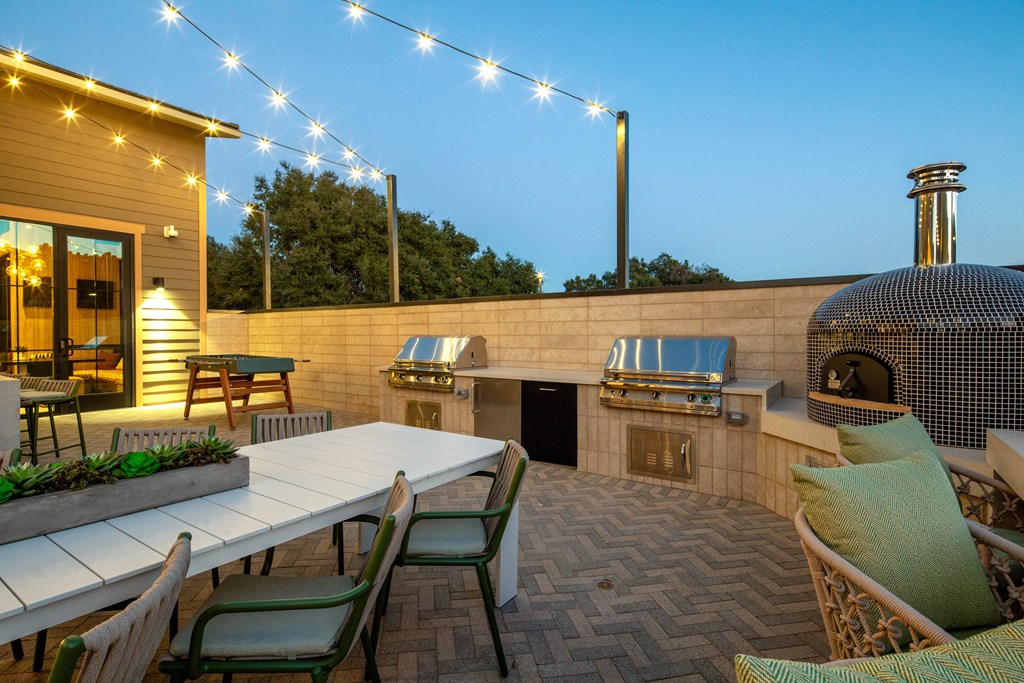 A patio with a table, chairs, and string lights.