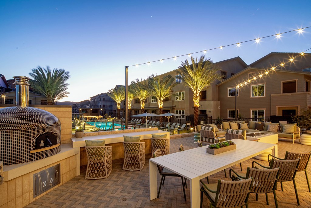 A backyard with a table, chairs, and a pizza oven.