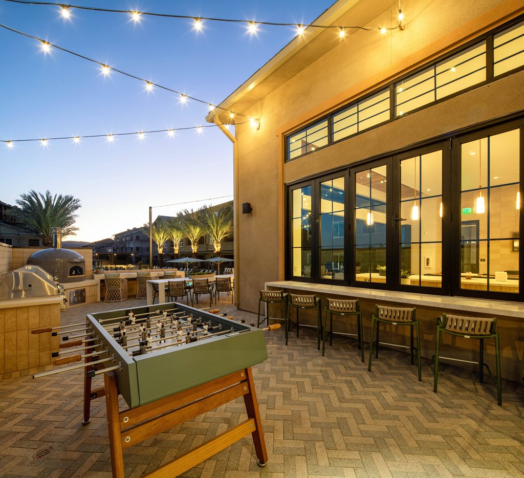 A table and chairs are set up on a patio with a pool table.