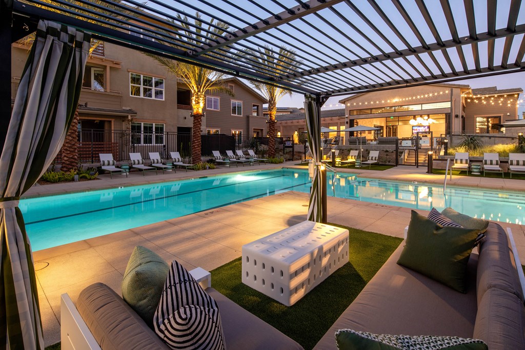 A poolside lounge area with a white couch and a striped pillow.