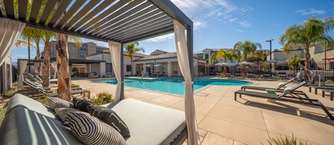 A pool area with sun loungers and a covered area.