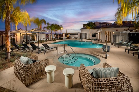A poolside area with wicker chairs and a pool.