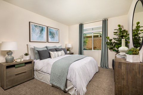 A bedroom with a bed, nightstands, and a plant.