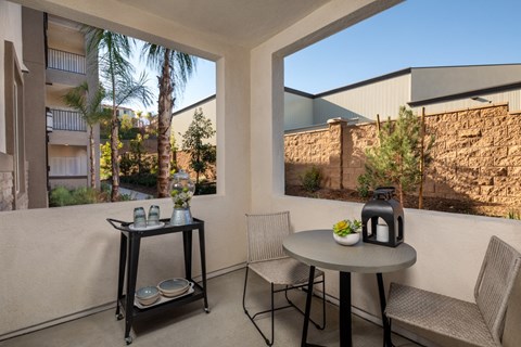 A patio with a table, chairs and a view of a building and trees.