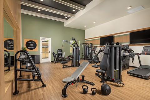 a gym with exercise equipment and weights on a wooden floor